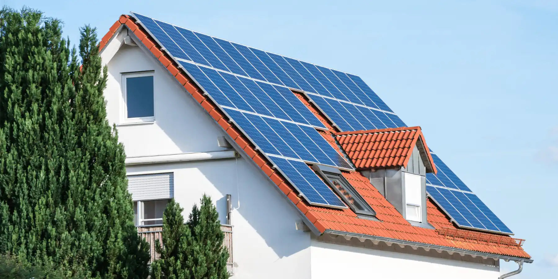 Weißes Haus mit Solarpanelen auf dem orangefarbenen tiled Dach.